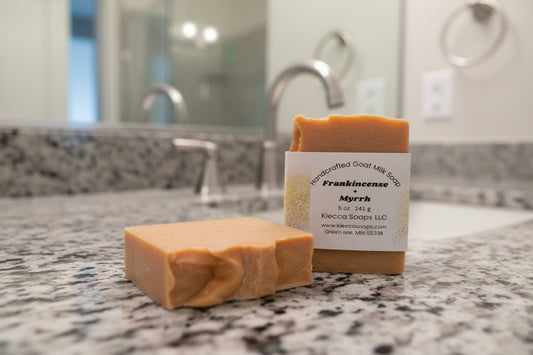 Two bars of soap, one with label on wooden surface.